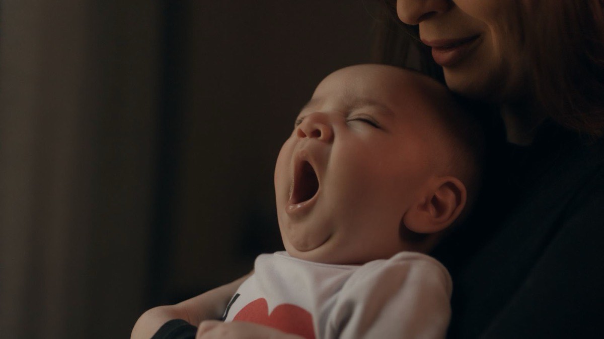 A baby yawning in a parent’s arms